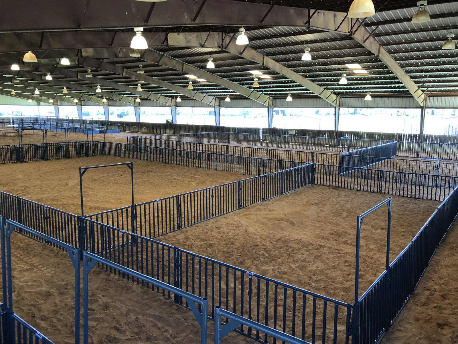 Blue pipe panel pens on a sand floor inside the Denton ISD covered arena