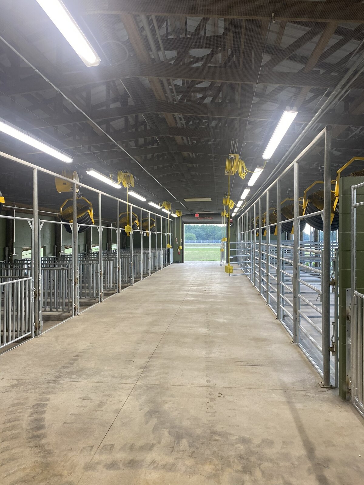 Long covered barn aisle lined with galvanized stalls at Katy ISD
